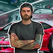 Логотип канала. Белый мужчина с татуировками, в кепке и с бородой на фоне гоночного авто стоит скрестив руки.